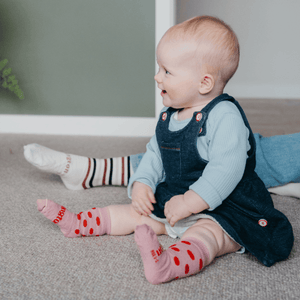 Baby wearing Lamington merino crew socks in soft pink with cherry red spots made in New Zealand.