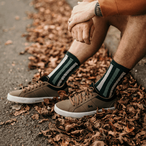 Man wearing Lamington merino crew socks in green and natural stripes made in New Zealand.