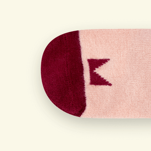 Close-up of Mosey by Lamington merino baby socks in plum showing knit texture and logo detail.
