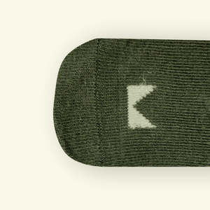 Close-up of Mosey by Lamington organic cotton baby socks in sage green showing rib knit texture and logo detail.