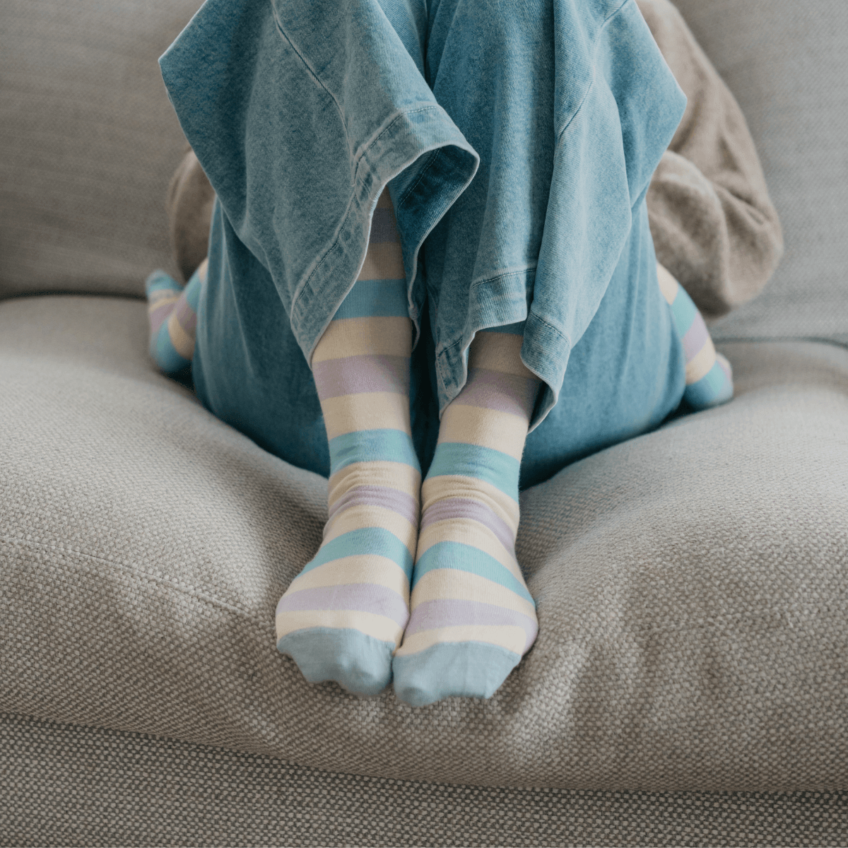 Woman wearing Lamington merino knee high socks with pastel blue, yellow, green and lilac stripes made in New Zealand.