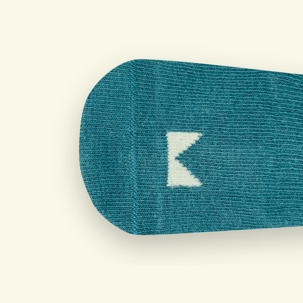 Close-up of Mosey by Lamington teal organic cotton baby socks in teal showing rib knit texture and logo detail.
