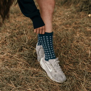 Woman wearing Lamington merino crew socks in deep teal with light blue grid pattern made in New Zealand