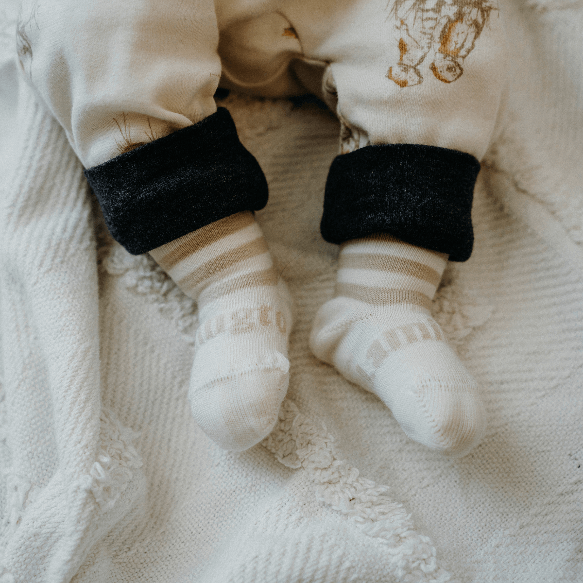 Merino Wool Crew Socks for Baby in Squirrel with oatmeal stripes on a cozy blanket.