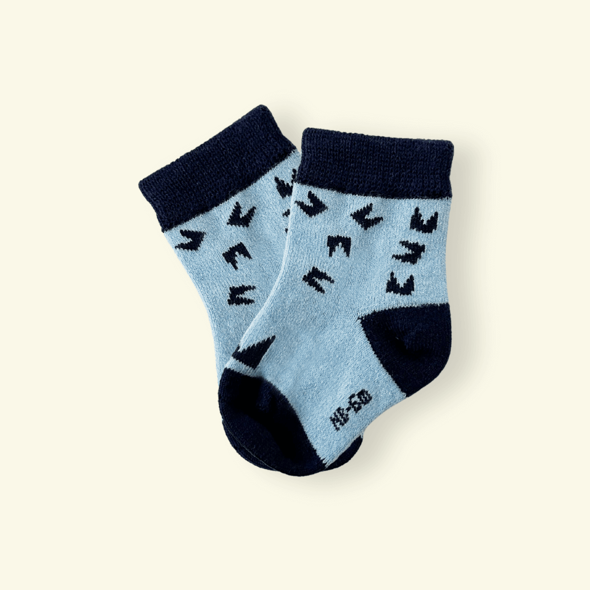 Mosey by Lamington merino baby socks in blue and navy with geometric pattern.