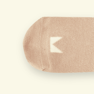 Close-up of Mosey by Lamington organic cotton baby socks in oatmeal showing rib knit texture and logo detail.