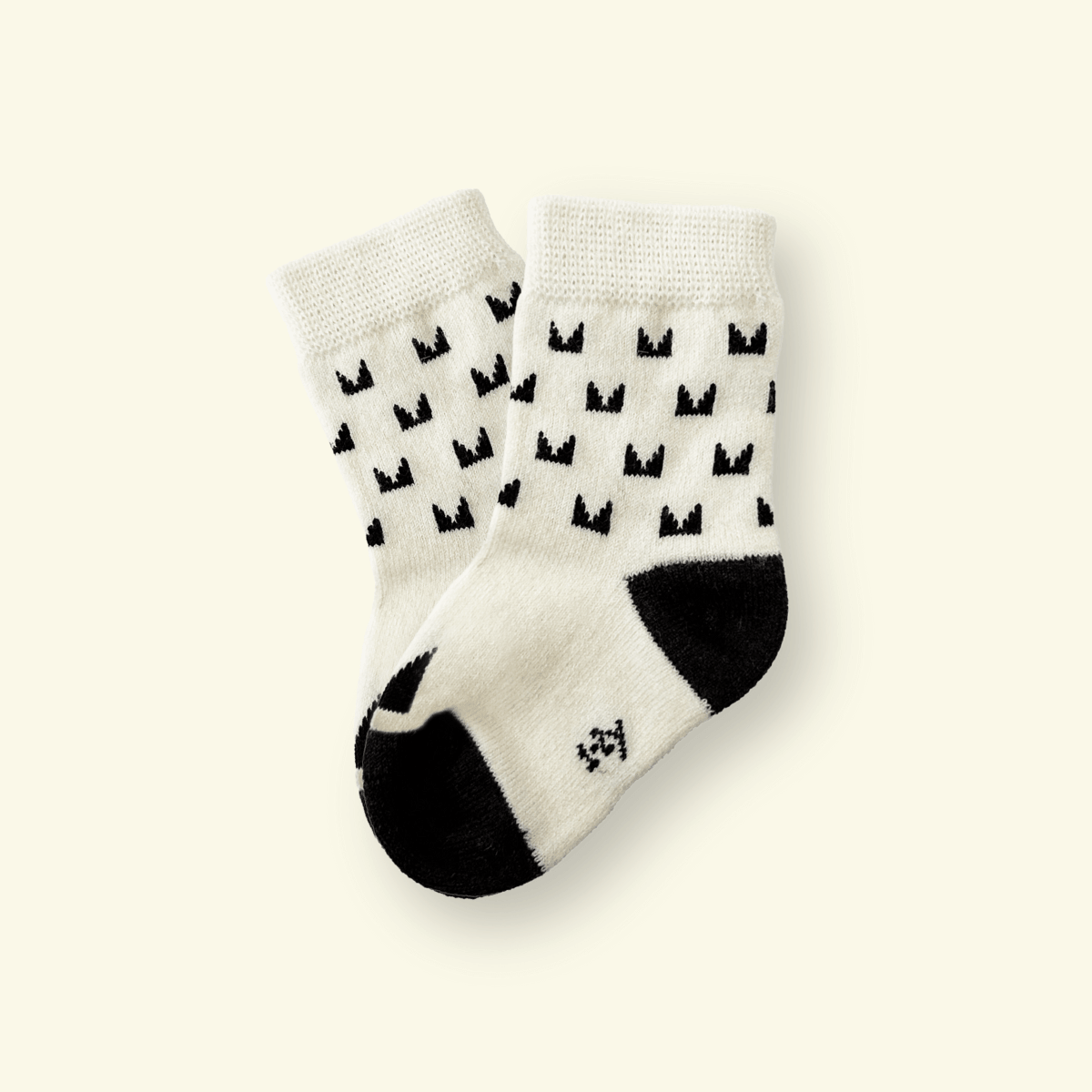 Mosey by Lamington merino baby socks in cream with black pattern.