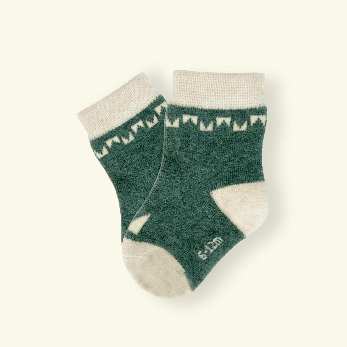 Mosey by Lamington merino baby socks in forest green with cream geometric pattern.
