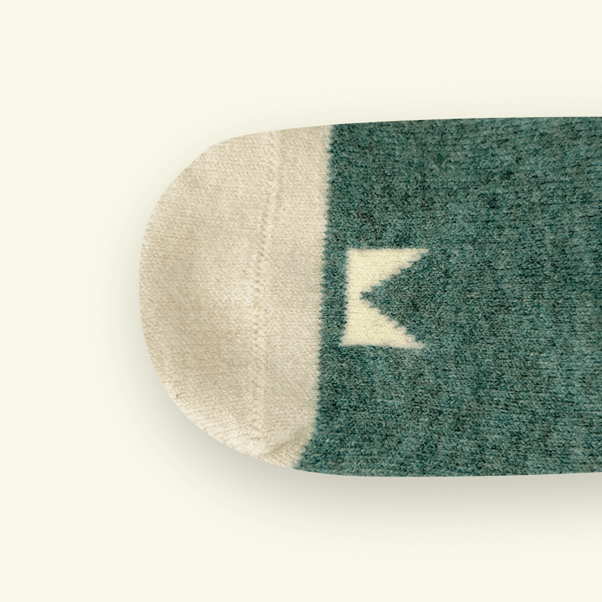 Mosey by Lamington merino baby socks in forest green with cream geometric pattern.