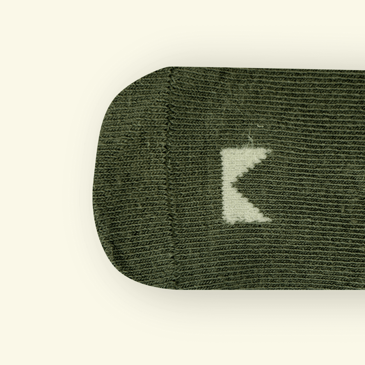 Close-up of Mosey by Lamington organic cotton baby socks in sage green showing rib knit texture and logo detail.